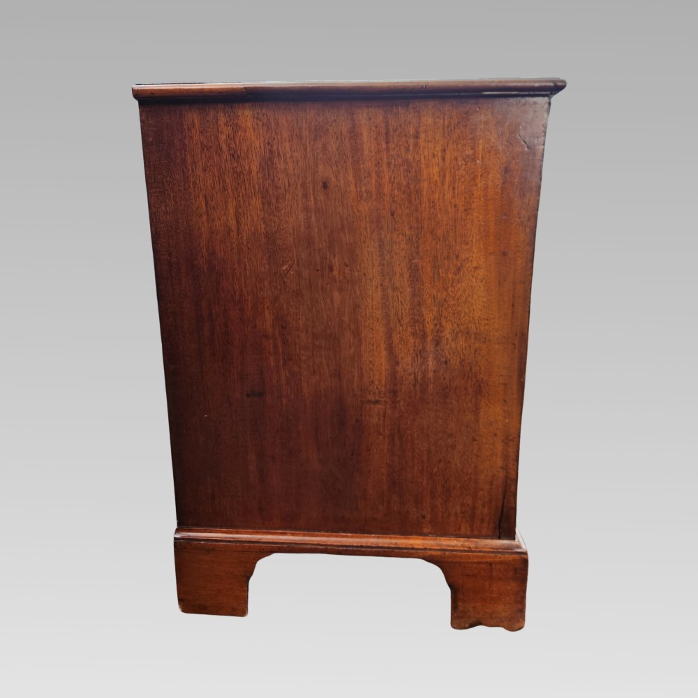 A Georgian mahogany chest of drawers featuring four graduated drawers with brass batwing handles, keyhole escutcheons, a brushing slide, and bracket feet. View VIII