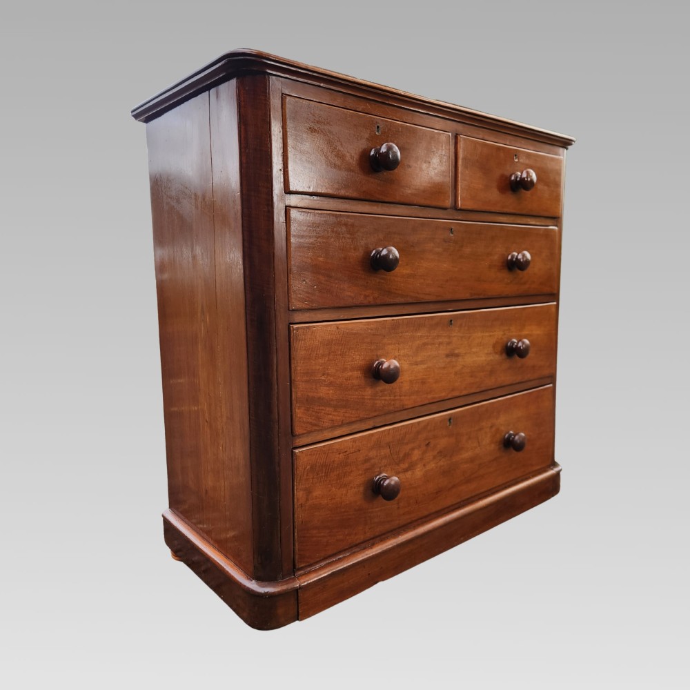 A Victorian mahogany chest of drawers featuring two short drawers above three full-width graduated drawers with turned wooden handles and a plinth base.