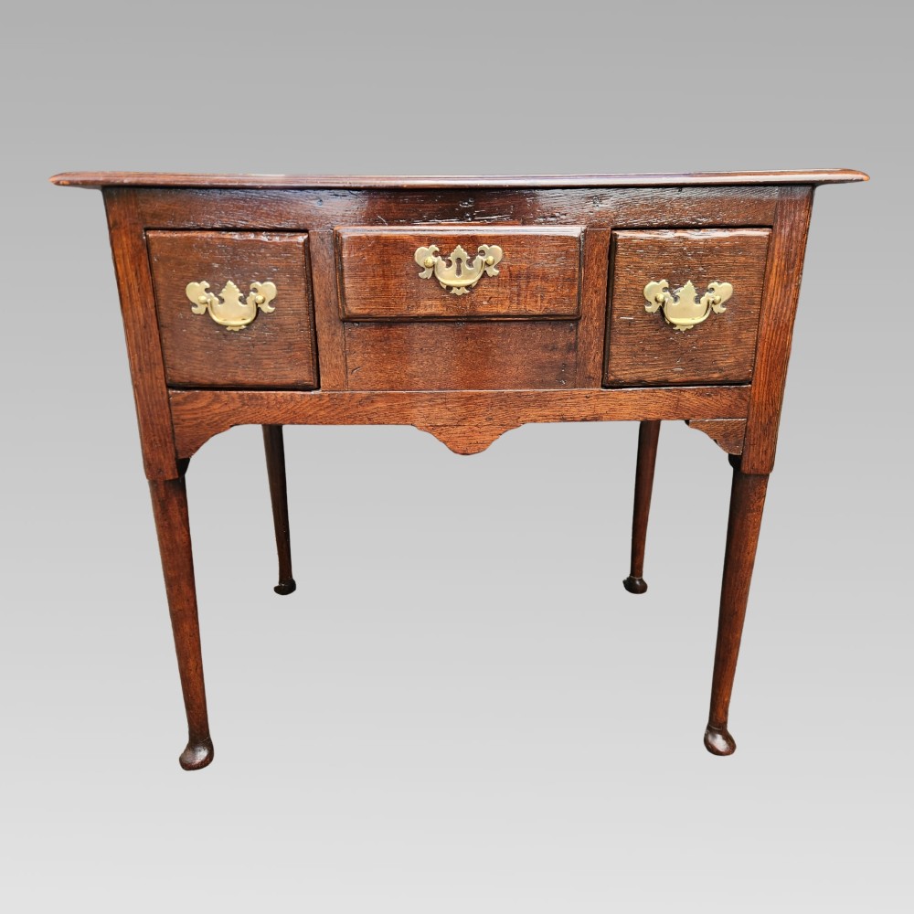 An antique Georgian oak lowboy side table featuring three front drawers with brass handles, a shaped apron, and four slender cabriole legs. View III