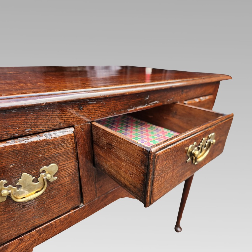 An antique Georgian oak lowboy side table featuring three front drawers with brass handles, a shaped apron, and four slender cabriole legs. View IV