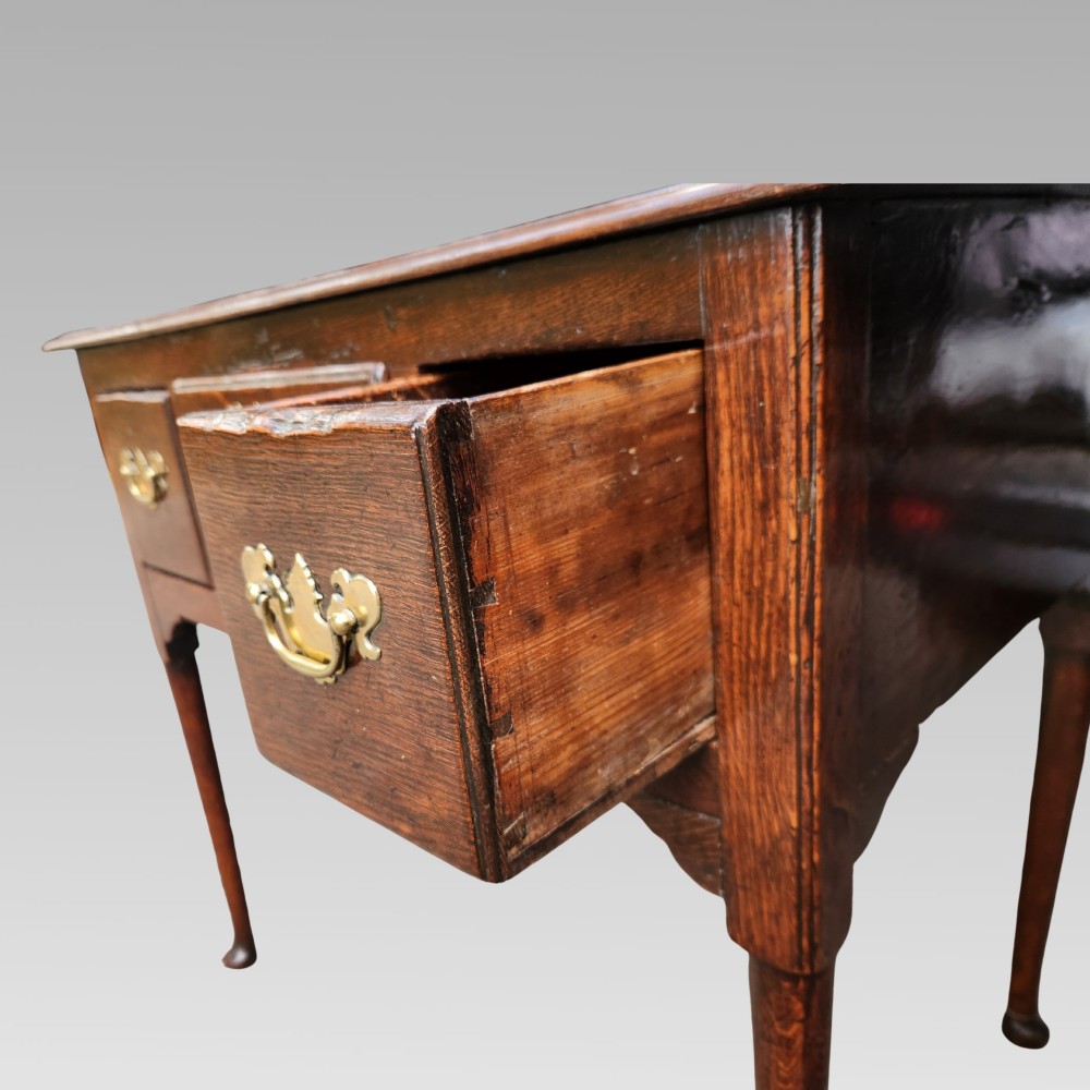 An antique Georgian oak lowboy side table featuring three front drawers with brass handles, a shaped apron, and four slender cabriole legs. View V