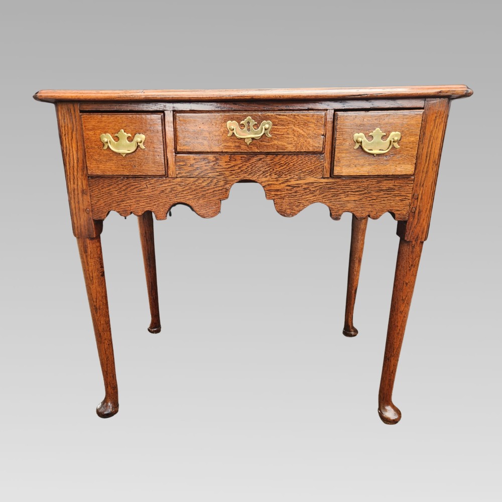 An antique Georgian oak lowboy side table featuring three drawers with brass handles, a shaped apron, and cabriole legs on pad feet. View III