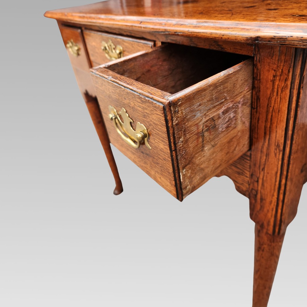 An antique Georgian oak lowboy side table featuring three drawers with brass handles, a shaped apron, and cabriole legs on pad feet. View IV