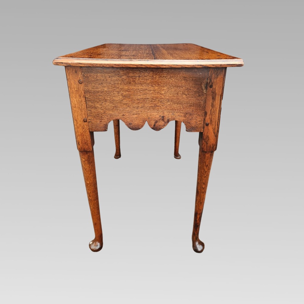 An antique Georgian oak lowboy side table featuring three drawers with brass handles, a shaped apron, and cabriole legs on pad feet. View V