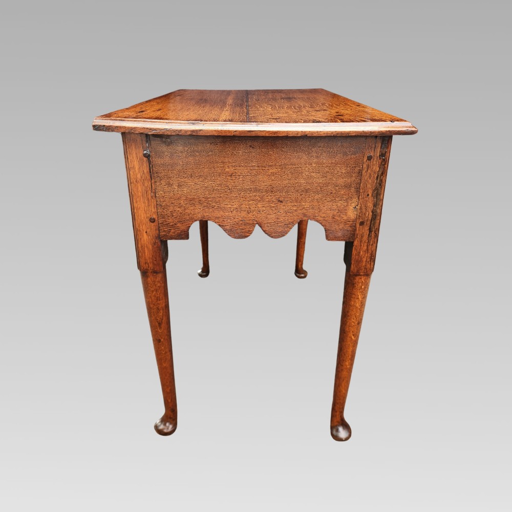 An antique Georgian oak lowboy side table featuring three drawers with brass handles, a shaped apron, and cabriole legs on pad feet. View VI