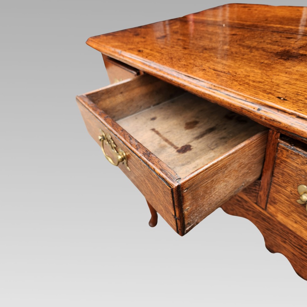 An antique Georgian oak lowboy side table featuring three drawers with brass handles, a shaped apron, and cabriole legs on pad feet. View VIII
