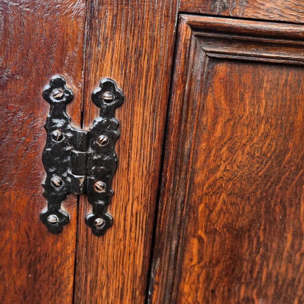 A dark brown Victorian English oak double-door storage cupboard with decorative black iron hinges and bun feet. View VII