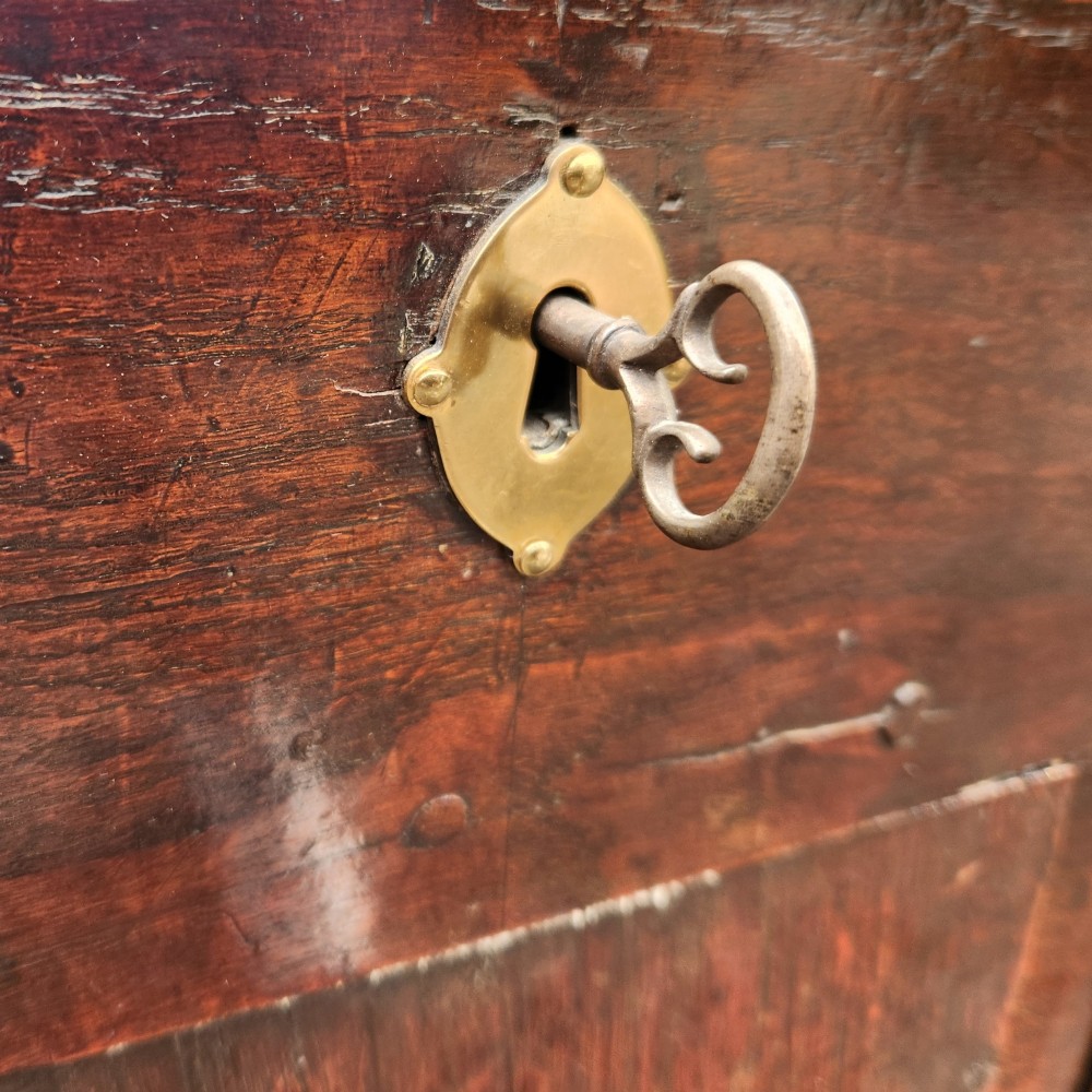 A 19th-century dark oak storage coffer featuring a hinged flat lid, panelled front construction, and a central brass keyhole escutcheon. View V