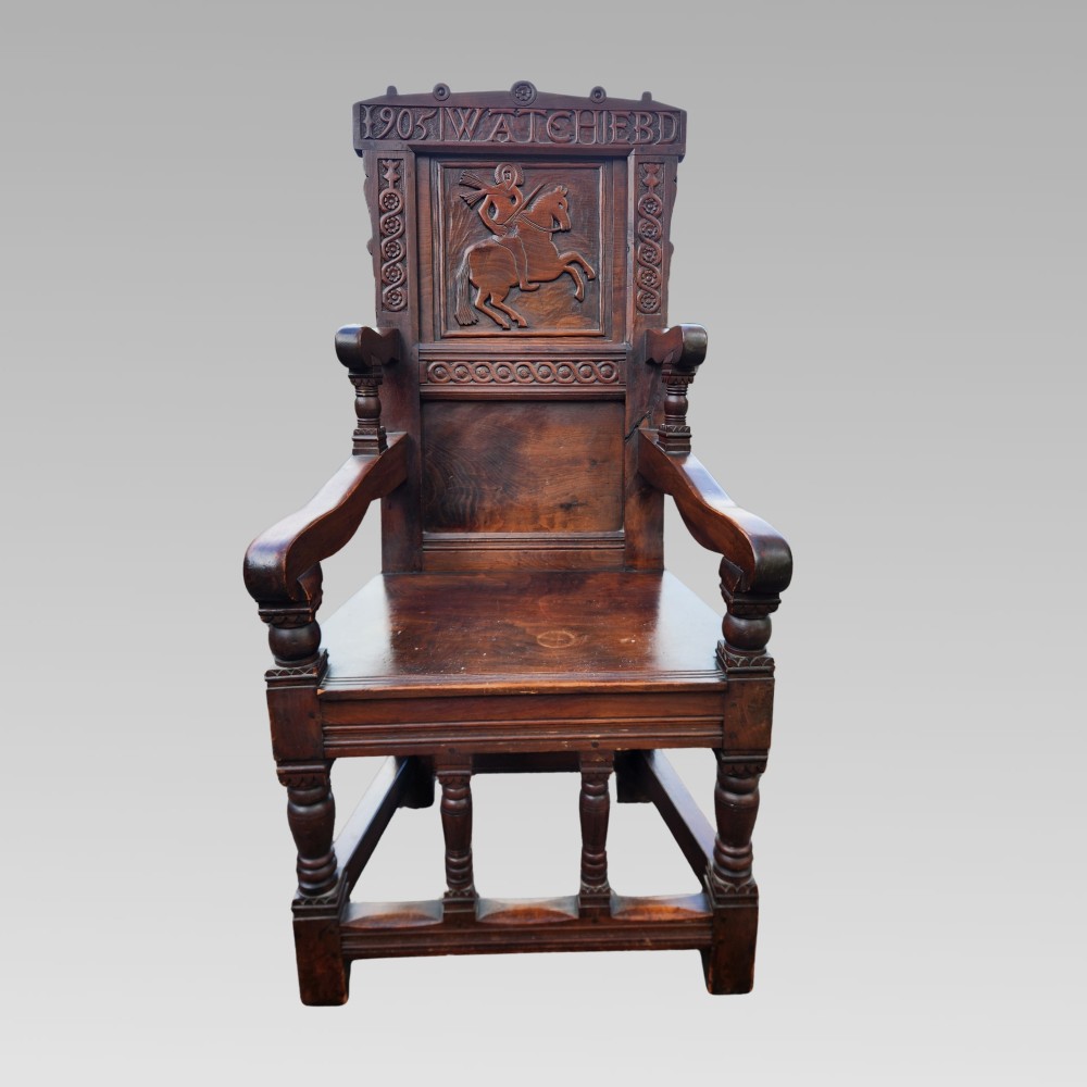 A dark oak wainscot armchair featuring a carved back panel with an equestrian motif, dated cresting rail, and turned legs. View II