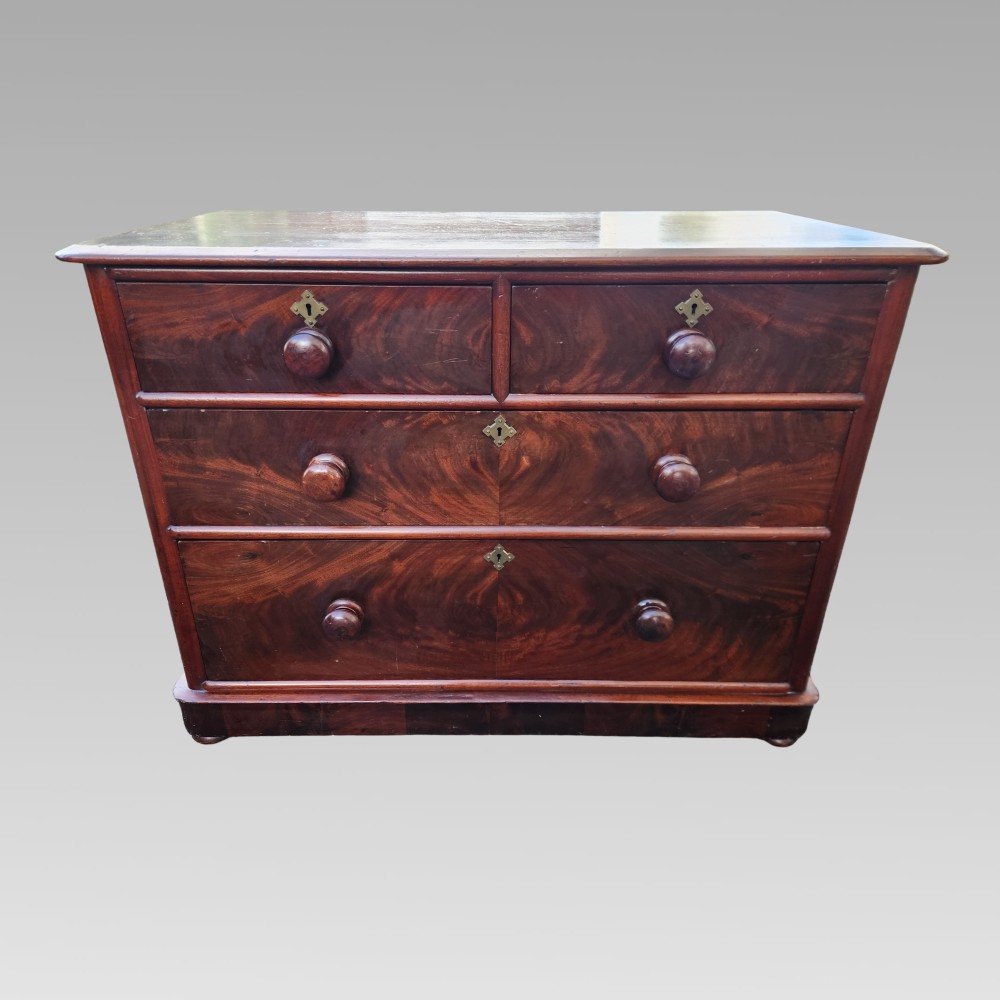 A Victorian mahogany chest of drawers featuring two short drawers over two long drawers with turned wooden handles, brass escutcheons, and a solid plinth base. View II