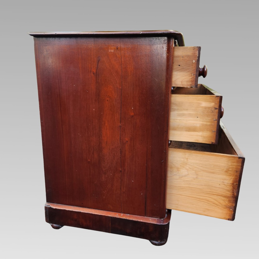 A Victorian mahogany chest of drawers featuring two short drawers over two long drawers with turned wooden handles, brass escutcheons, and a solid plinth base. View IV