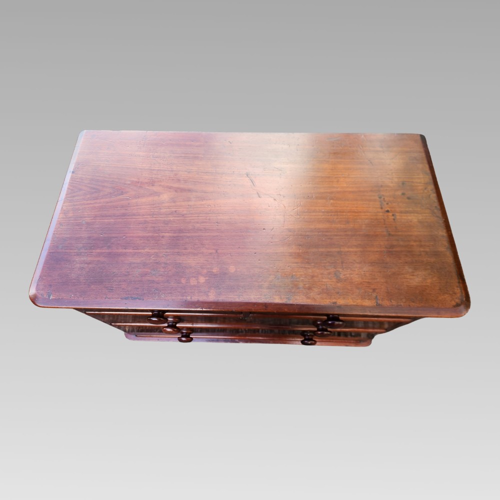 A Victorian mahogany chest of drawers featuring two short drawers over two long drawers with turned wooden handles, brass escutcheons, and a solid plinth base. View V