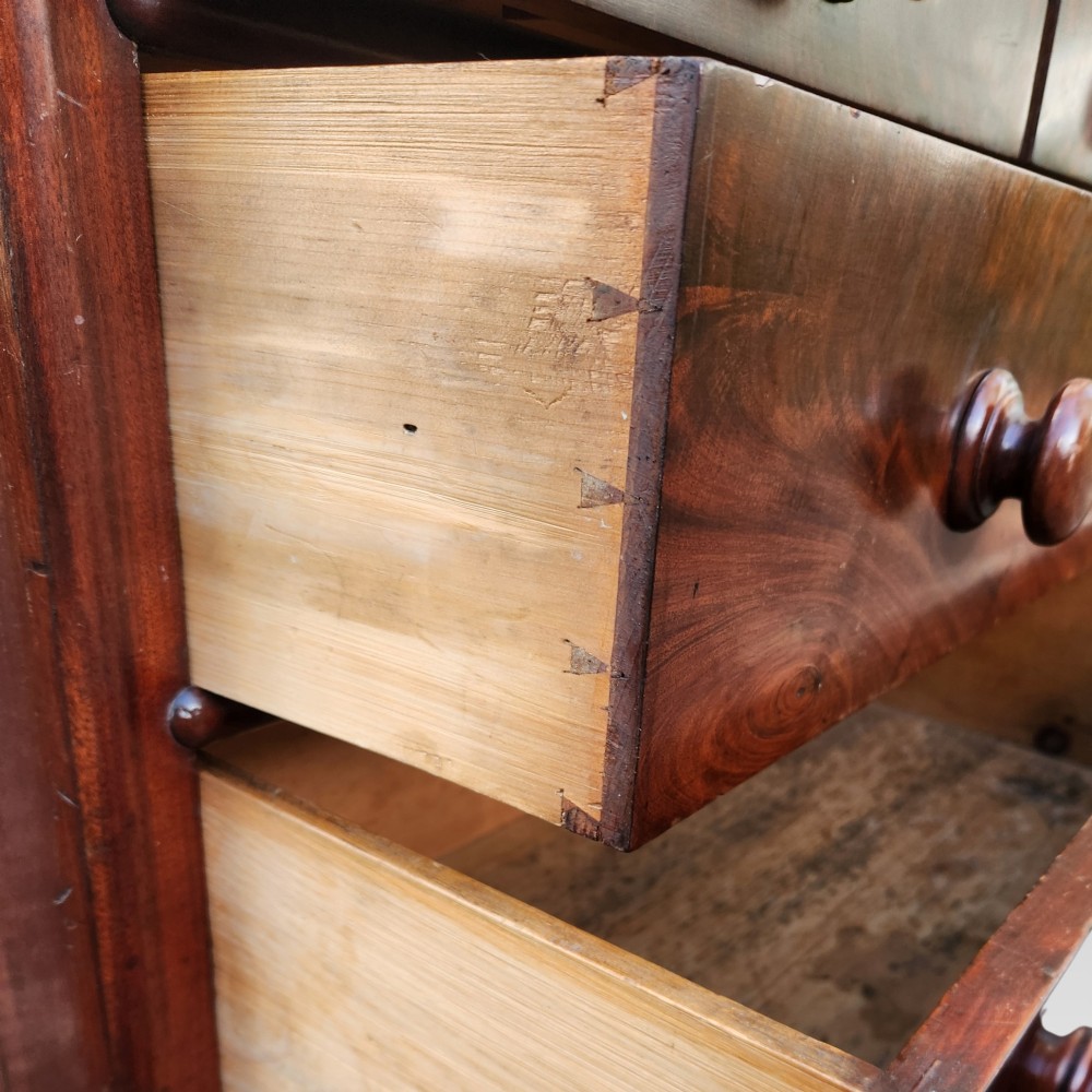 A Victorian mahogany chest of drawers featuring two short drawers over two long drawers with turned wooden handles, brass escutcheons, and a solid plinth base. View VI