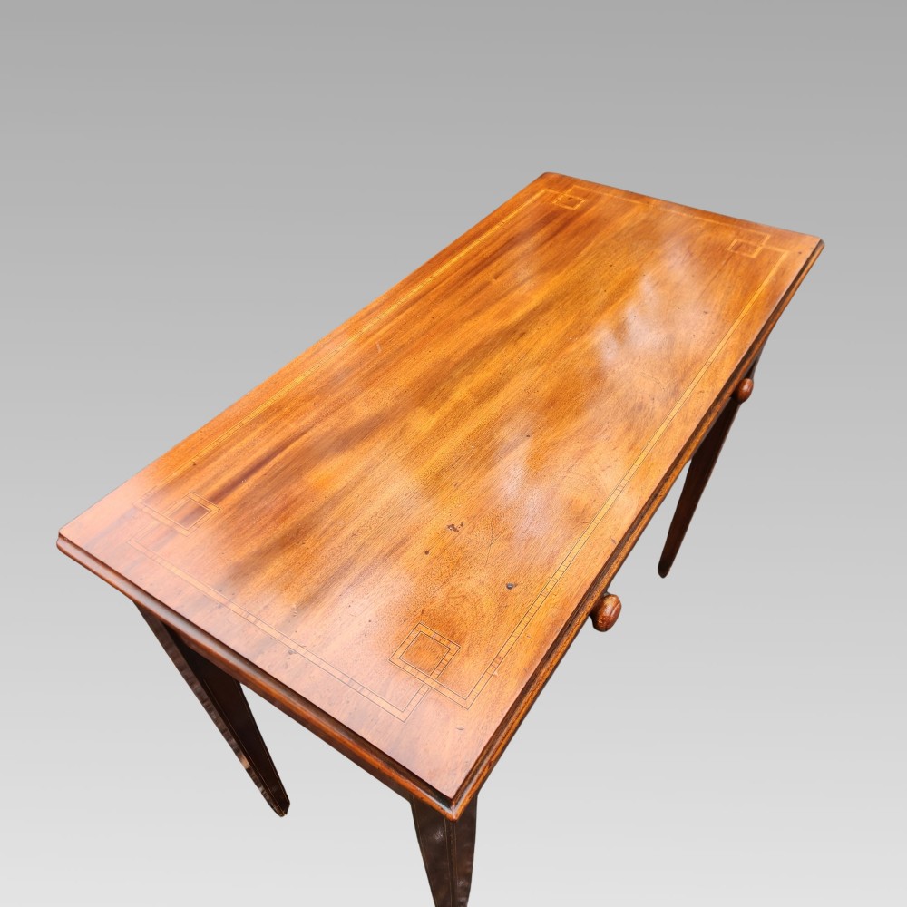 A Victorian mahogany side table featuring decorative satinwood geometric inlay on the rectangular top, two drawers with wooden knobs, and four tapered legs. View II