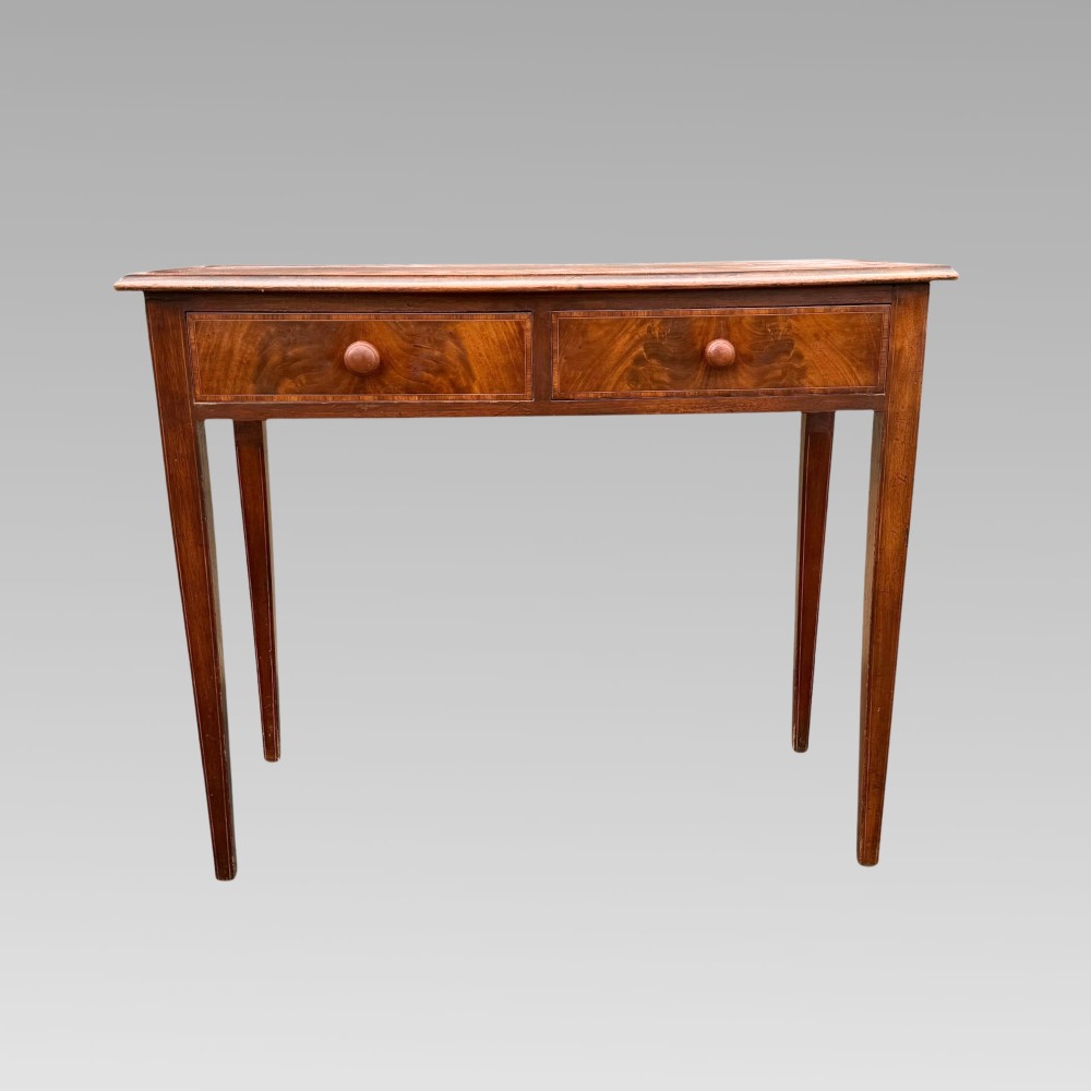 A Victorian mahogany side table featuring decorative satinwood geometric inlay on the rectangular top, two drawers with wooden knobs, and four tapered legs. View VI