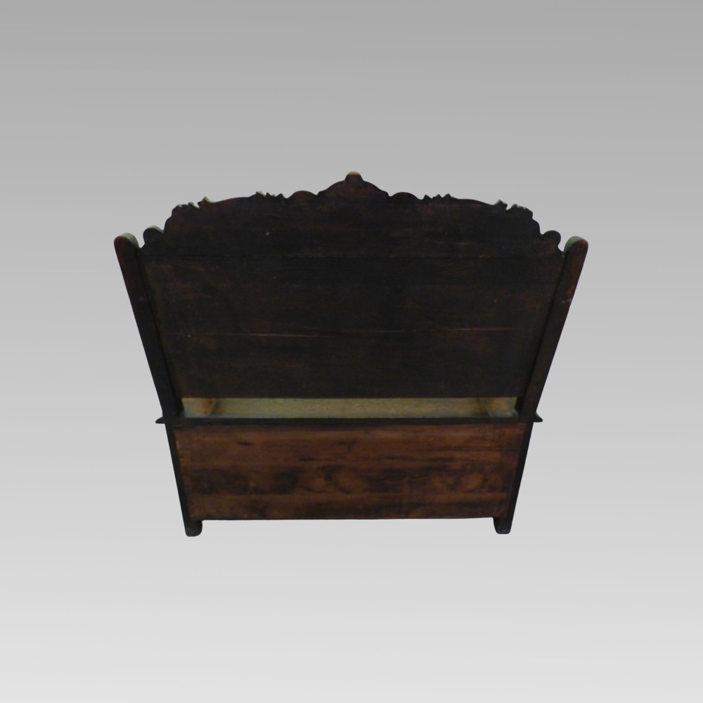 Carved dark oak hall settle featuring a cresting rail, panelled back, curved armrests, and a hinged storage seat. View III