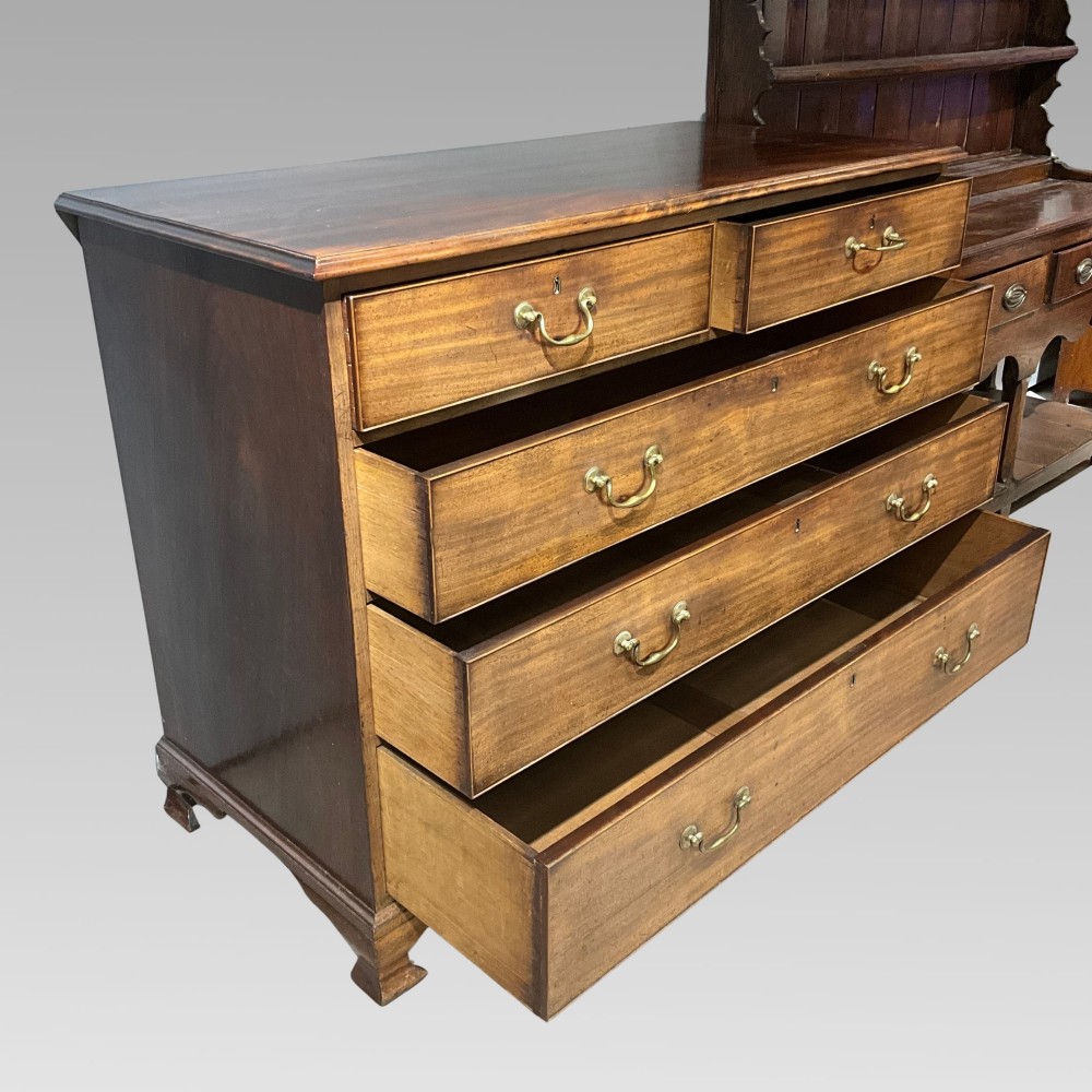 A Georgian mahogany chest of drawers with a two-over-three drawer configuration, brass swan-neck handles, and bracket feet. View II