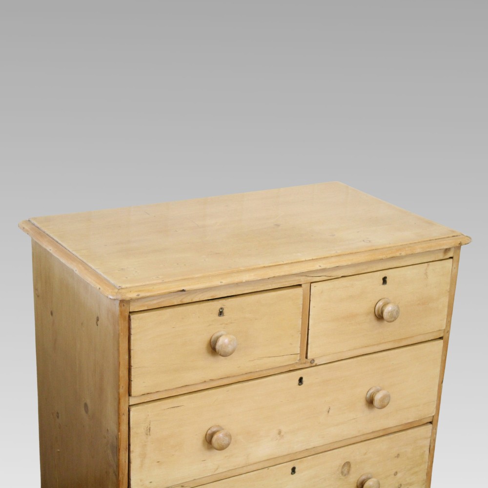 A Victorian pine chest of drawers featuring two short drawers over two long drawers with turned wooden knobs and a solid plinth base. View II