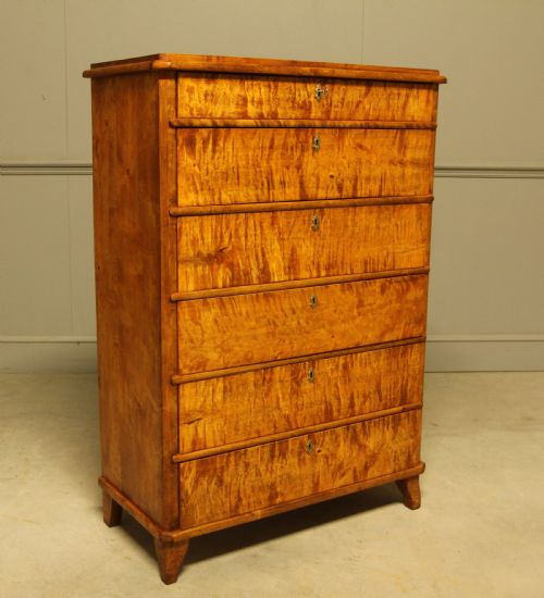 fig 1. An early twentieth-century Swedish tall chest of drawers crafted in figured golden satin birch with six graduated drawers and brass escutcheons.