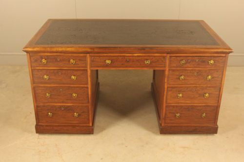 fig 1. A 19th-century mahogany partners desk featuring a dark leather writing inset top, nine drawers on the front with brass ring handles, and twin pedestal bases.