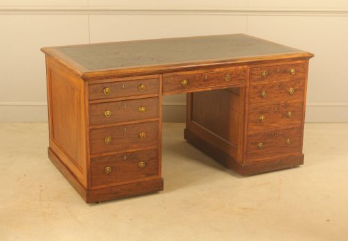 fig 2. A 19th-century mahogany partners desk featuring a dark leather writing inset top, nine drawers on the front with brass ring handles, and twin pedestal bases.