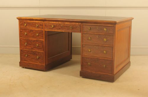 fig 3. A 19th-century mahogany partners desk featuring a dark leather writing inset top, nine drawers on the front with brass ring handles, and twin pedestal bases.