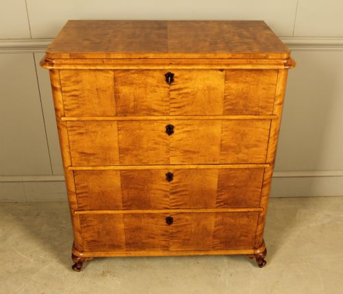 fig 1. A 19th-century Swedish chest of drawers crafted from flame birch veneer with four horizontal drawers, central dark escutcheons, and short carved bracket feet.
