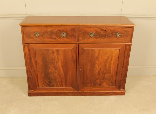 fig 1. An Edwardian curl mahogany two-door sideboard featuring two top drawers with brass ring handles and panelled cupboard doors on a plinth base.
