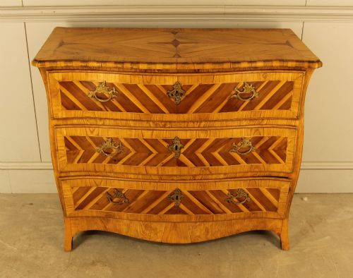 fig 1. An 18th-century Swedish Rococo bombe chest of drawers featuring geometric chevron parquetry inlays, curved sides, three long drawers, and cast brass hardware.
