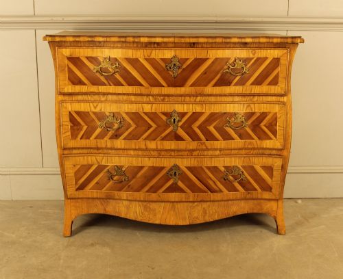 fig 2. An 18th-century Swedish Rococo bombe chest of drawers featuring geometric chevron parquetry inlays, curved sides, three long drawers, and cast brass hardware.