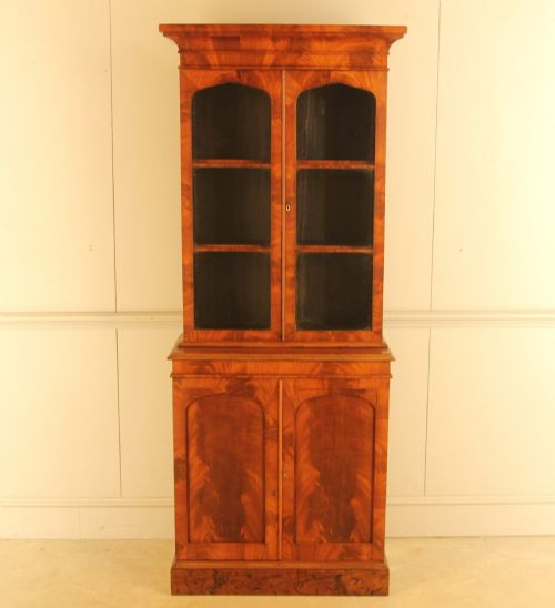 fig 1. A two-door 19th-century mahogany bookcase featuring an upper glazed display section with internal shelves above a lower cabinet with flame mahogany panelled doors.