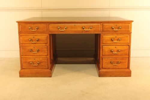 fig 3. An early 20th-century golden oak twin-pedestal bankers desk featuring a dark leather inset top, nine drawers with brass handles, and panelled sides.