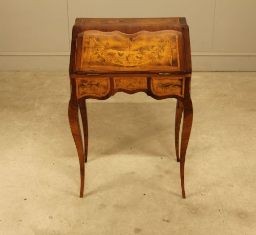 fig 1. A 19th-century Italian walnut writing bureau featuring floral marquetry inlay, a slanted fall front, and slender cabriole legs.