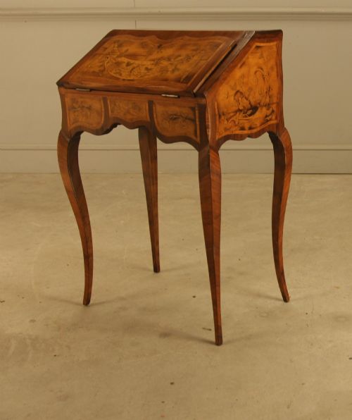 fig 2. A 19th-century Italian walnut writing bureau featuring floral marquetry inlay, a slanted fall front, and slender cabriole legs.