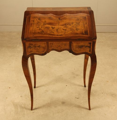 fig 4. A 19th-century Italian walnut writing bureau featuring floral marquetry inlay, a slanted fall front, and slender cabriole legs.