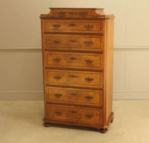 fig 3. A tall 19th-century Swedish burr walnut chest of drawers featuring seven drawers, crossbanded inlay, ornate brass handles, and a stepped top section.
