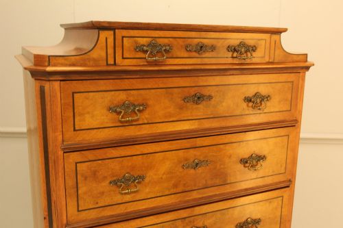 fig 4. A tall 19th-century Swedish burr walnut chest of drawers featuring seven drawers, crossbanded inlay, ornate brass handles, and a stepped top section.