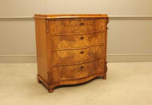 fig 1. A 19th-century Swedish burr walnut chest of drawers featuring a serpentine front, four graduated drawers, brass escutcheons, and carved side pilasters.