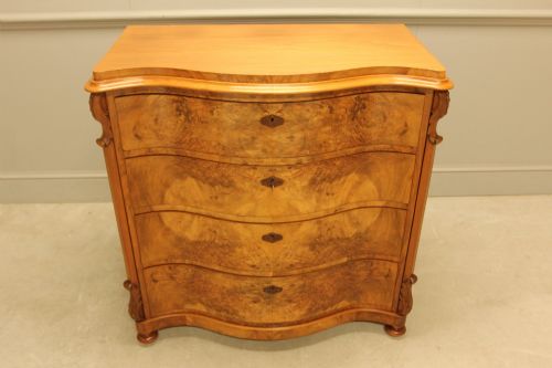 fig 4. A 19th-century Swedish burr walnut chest of drawers featuring a serpentine front, four graduated drawers, brass escutcheons, and carved side pilasters.