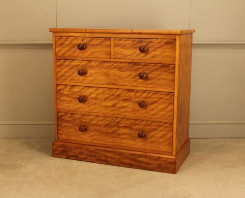 fig 2. A Victorian stained birch chest of drawers featuring a two short over three long drawer configuration with turned wooden knobs and a solid plinth base.