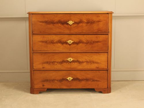 fig 1. A nineteenth-century Swedish curl mahogany secretaire chest featuring three long drawers below a fold-down desk surface revealing fitted interior drawers.