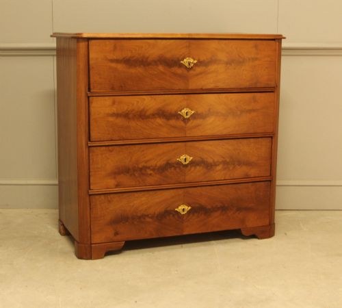fig 2. A nineteenth-century Swedish curl mahogany secretaire chest featuring three long drawers below a fold-down desk surface revealing fitted interior drawers.