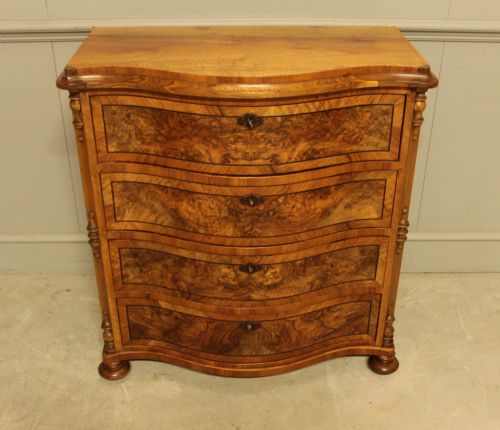 fig 3. A 19th-century Swedish burr walnut chest featuring four serpentine-front drawers, bookmatched veneers, turned side pilasters, and bun feet.