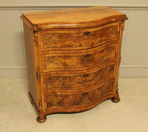 fig 4. A 19th-century Swedish burr walnut chest featuring four serpentine-front drawers, bookmatched veneers, turned side pilasters, and bun feet.