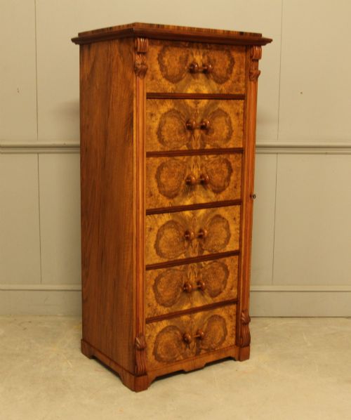 fig 1. A tall 19th-century Swedish Wellington chest featuring six book-matched burr walnut drawers with turned handles, flanked by carved pilasters.