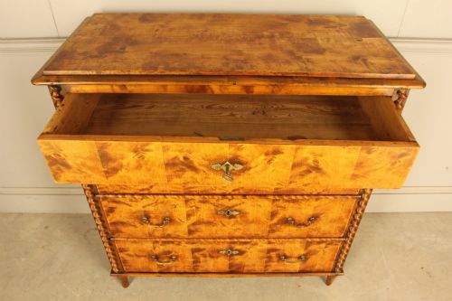 fig 4. A nineteenth-century Swedish chest of drawers crafted from highly figured flame birch veneer, featuring four full-width drawers with brass drop handles, brass escutcheons, and spiral-twisted side columns.