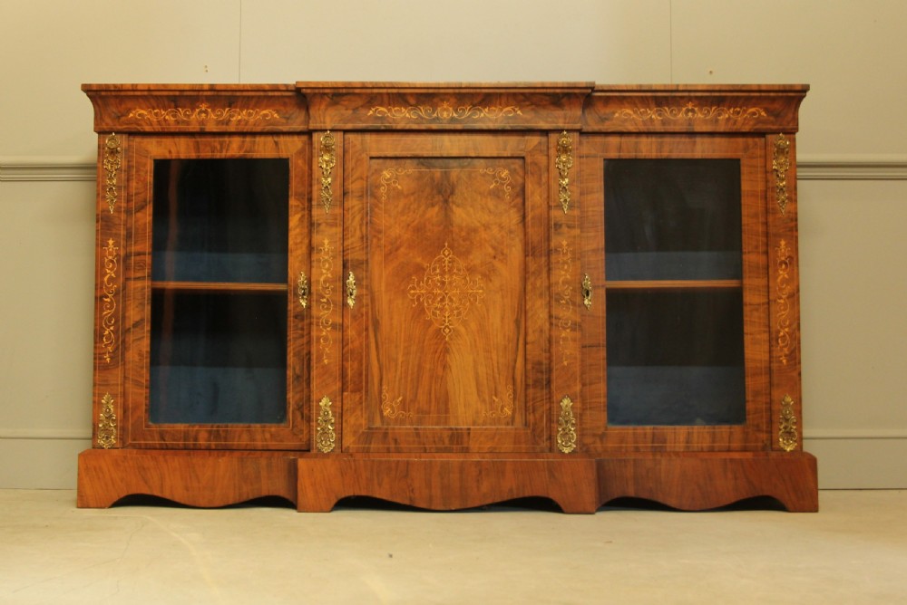 A Victorian low breakfront credenza crafted from burr walnut with marquetry inlay, gilt-brass mounts, a central panelled door, and two outer glazed doors. View II
