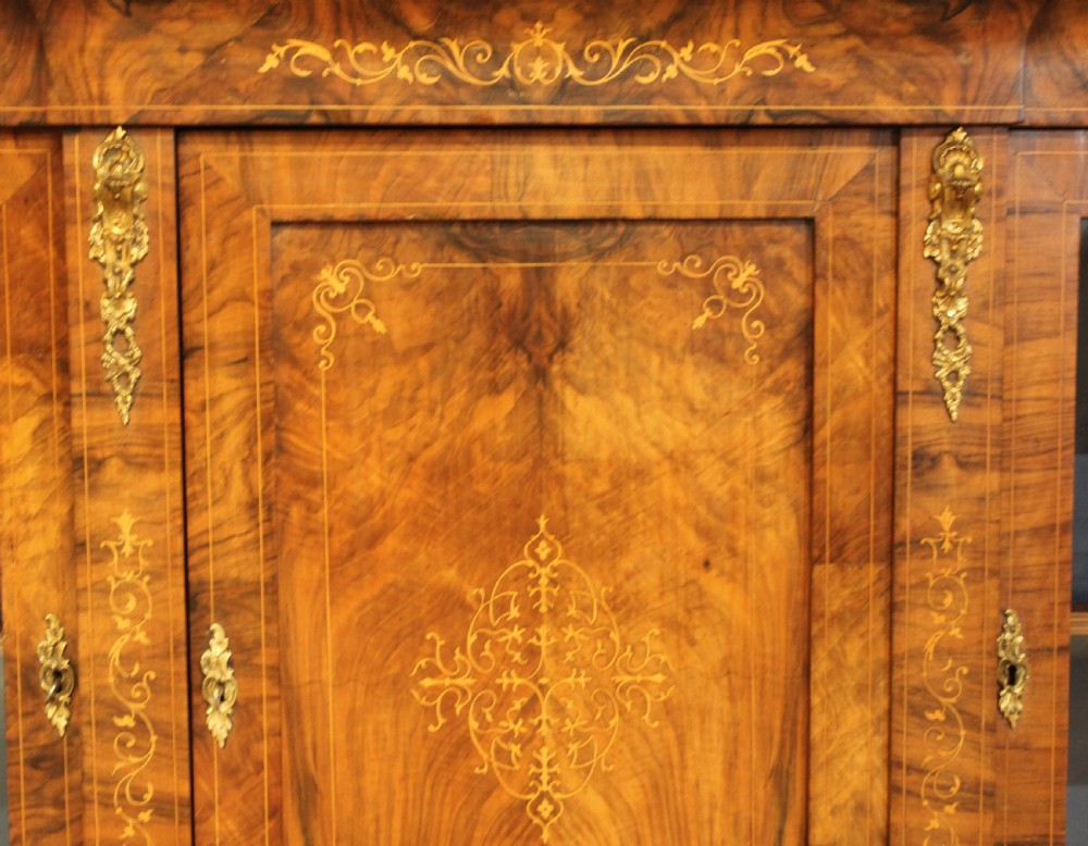 A Victorian low breakfront credenza crafted from burr walnut with marquetry inlay, gilt-brass mounts, a central panelled door, and two outer glazed doors. View XI
