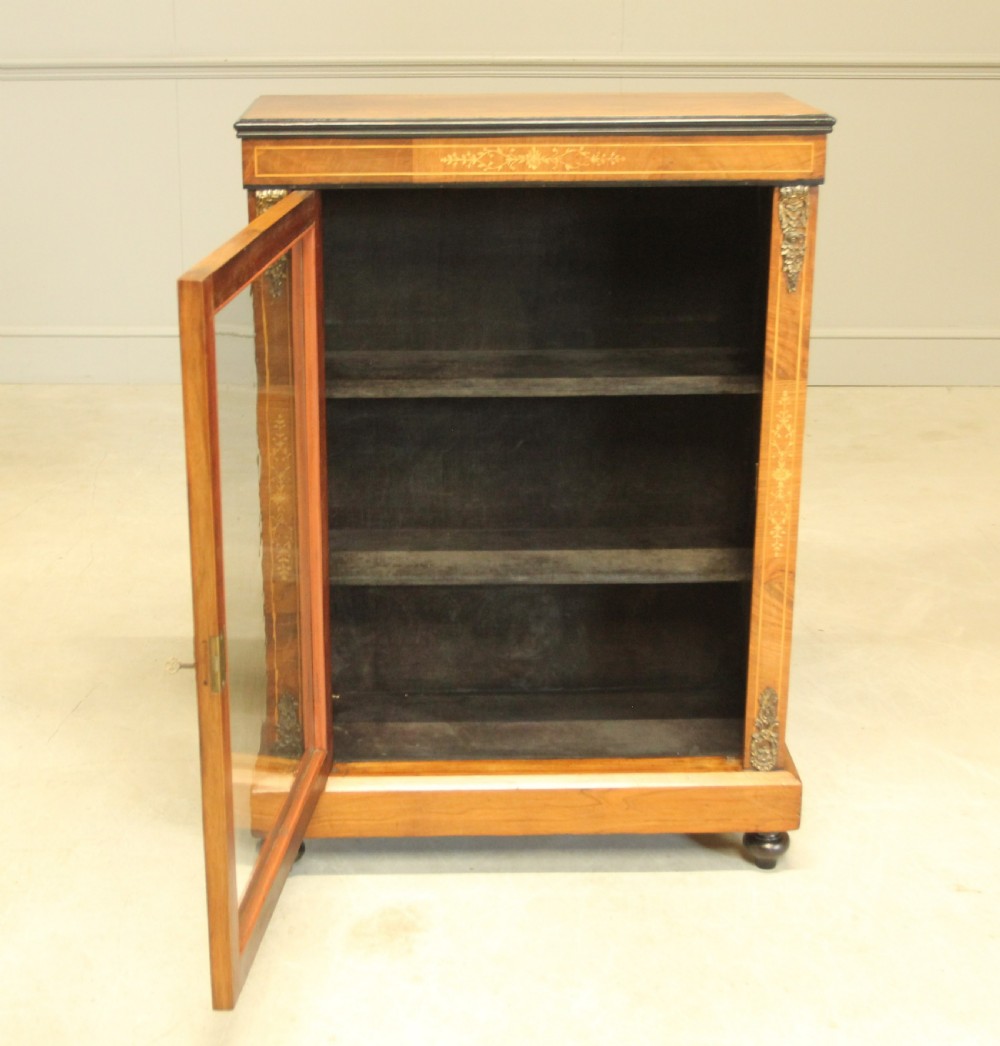 A Victorian walnut pier display cabinet featuring a single glazed door, floral marquetry inlay, decorative brass mounts, and turned feet. View VII