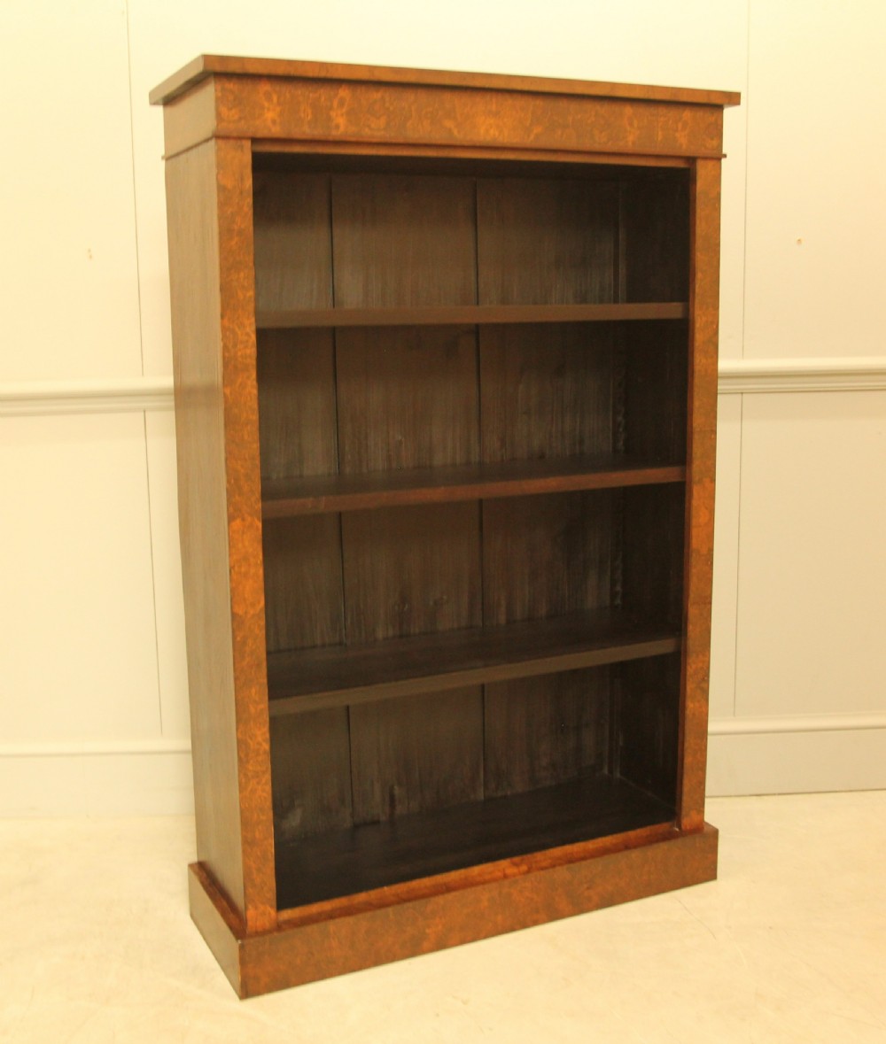 A Victorian open bookcase featuring faux burr walnut outer framing, dark interior shelves, and a solid plinth base. View V